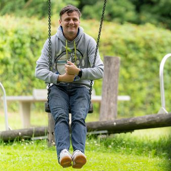 Ein Softwareentwickler schaukelt auf einem Spielplatz.